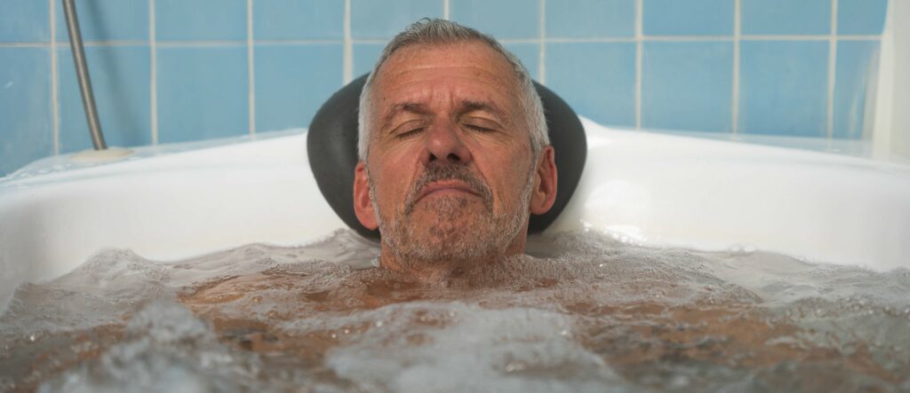 homme avec les yeux fermés se relaxant dans un bain